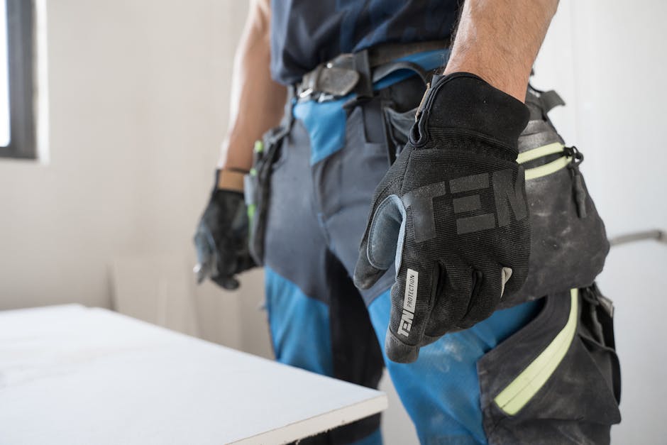 Close-up of a construction worker wearing safety gloves indoors, focused on hand protection. Close-up of a construction worker wearing safety gloves indoors, focused on hand protection.