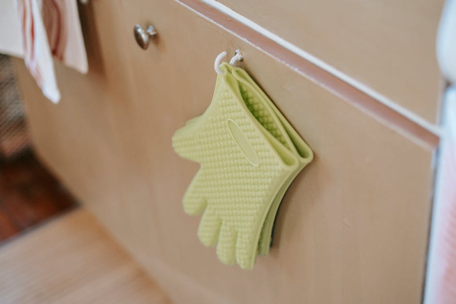 Sarung tangan oven silikon hijau digantung di lemari dapur, menampilkan desain dan fungsionalitas modern.