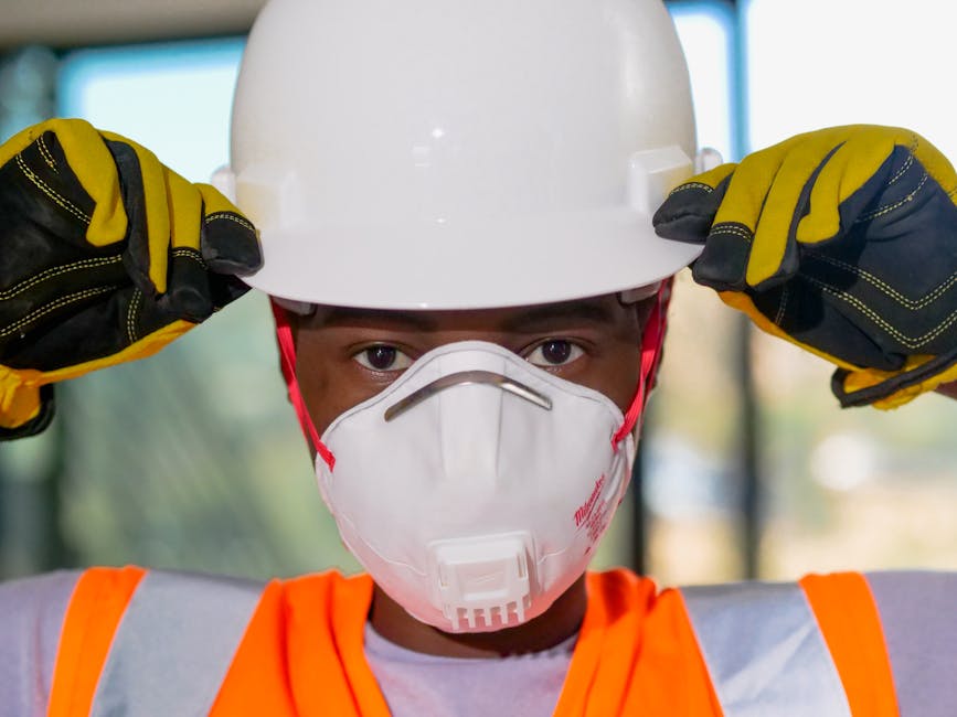 Primo piano di un operaio edile che indossa dispositivi di protezione individuale, tra cui casco, mascherina N95 e guanti. Primo piano di un operaio edile che indossa dispositivi di protezione individuale, tra cui casco, mascherina N95 e guanti.
